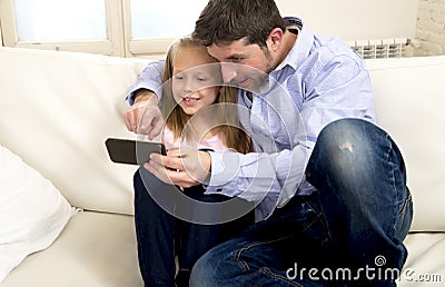 Young happy father showing sweet little girl using internet on mobile phone having fun together Stock Photo