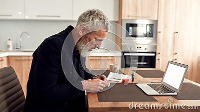 Young happy girl in headphones holding handbook and explaining something to teacher or tutor while having online lesson Stock Photo