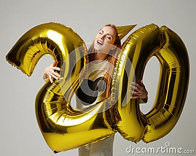 Young happy girl with huge gold digit twenty balloons as a present for birthday Stock Photo