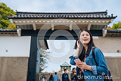 Young happy girl standing the entrance of the osaka castle. elegant attractive traveler flick hair and enjoying looking around the Stock Photo