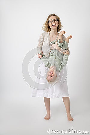 Young happy gorgeous woman mother holding amazing little girl daughter upside down having fun, playing games. Childhood. Stock Photo