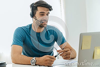 Young happy handsome man student wear headphone listen online course communicate from home, coronavirus COVID-19 outbreak, video Stock Photo