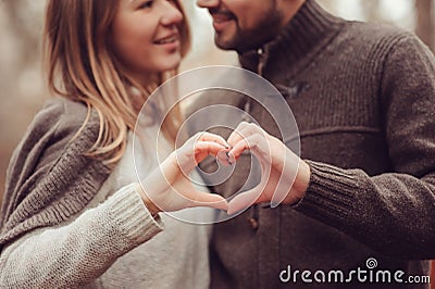 Young happy loving couple showing heart for valentine day on cozy outdoor walk in forest Stock Photo