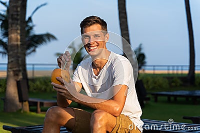 Young happy man drinks a fresh coconut Stock Photo