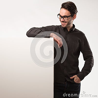 Young happy man showing presentation, pointing on placard over gray background Stock Photo