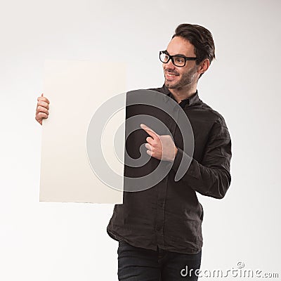 Young happy man showing presentation, pointing on placard over gray background Stock Photo