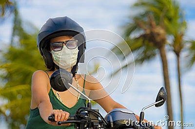 Young happy and pretty Asian Chinese woman riding scooter wearing motorcycle helmet and protective face mask in motorbike safe rid Stock Photo