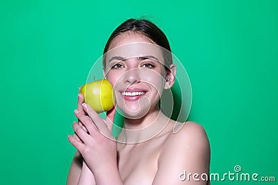 Young happy smiling woman bitting apple, healthy lifestyle. Girls holds a fresh green apple studio portrait on green Stock Photo