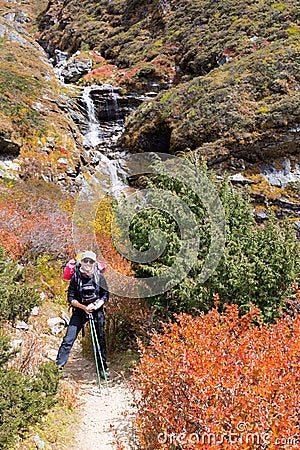 Young happy woman backpacker standing mountain waterfall. Stock Photo