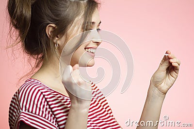 Young happy woman with checking result of a one-time pregnancy test, family planning, motherhood concept on pink studio background Stock Photo