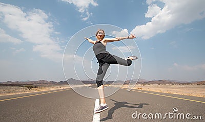 Young happy woman on an empty road in Oman desert. Stock Photo