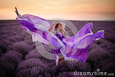 Young happy woman in luxurious purple dress standing in lavender field Stock Photo