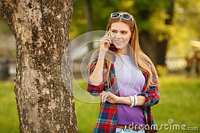 Young happy woman talking on cell phone in summer city park. Beautiful modern girl in sunglasses with a smartphone, outdoor Stock Photo