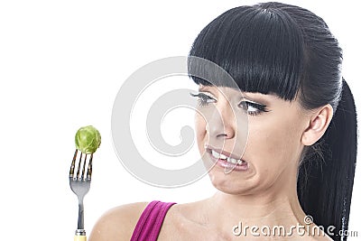 Young Healthy Woman with Disgusted Expression with Distaste to a Brussels Sprout on a Fork Stock Photo