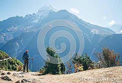 Young hiker backpacker man using trekking poles enjoying the Thamserku 6608m mountain with flying rescue helicopter during high Stock Photo