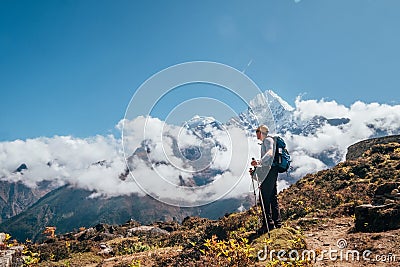 Young hiker backpacker man using trekking poles enjoying the Thamserku 6608m mountain during high altitude Acclimatization walk. Stock Photo