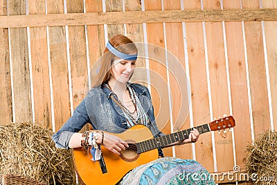 Young hippie woman play guitar in barn Stock Photo