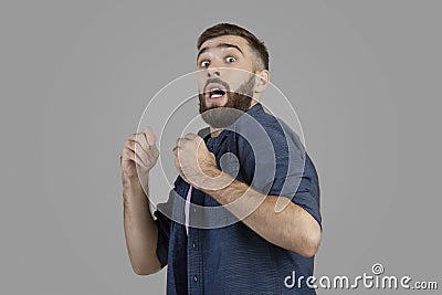 Young hipster guy being scared or terrified over grey studio background. Negative human emotions and feelings concept Stock Photo