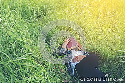 Young hipster man lying down on grassland napping tired after re Stock Photo