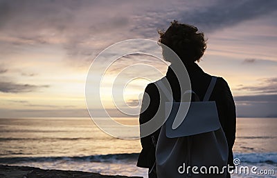 Young hipster relax on the beach on background ocean sunrise, silhouette romantic person looking view evening seascape, girl enjoy Stock Photo