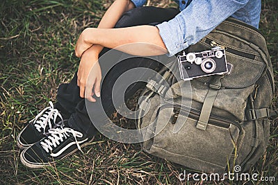 Young hipster traveller woman with backpack sitting in the grass Stock Photo