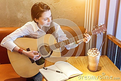 Young girl playing guitar in cafe Stock Photo