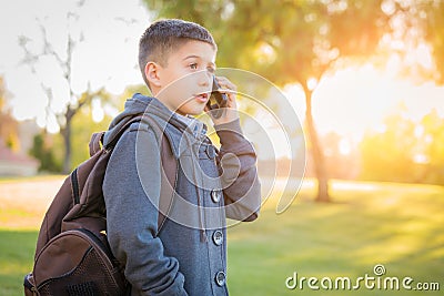Young Hispanic Boy Walking Outdoors With Backpack Talking on Cell Phone Stock Photo
