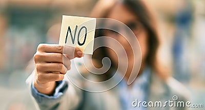 Young hispanic businesswoman with serious expression holding reminder with no message at the city Stock Photo