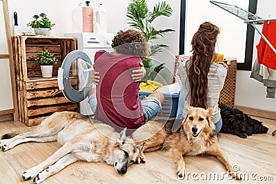 Young hispanic couple doing laundry with dogs hugging oneself happy and positive from backwards Stock Photo
