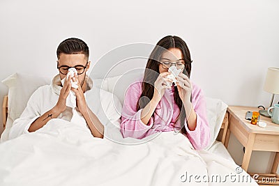 Young hispanic couple sick lying in bed at home Stock Photo