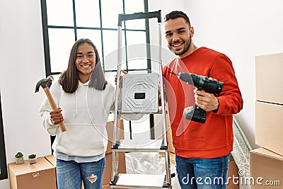 Young hispanic couple smiling happy repairing new home Stock Photo