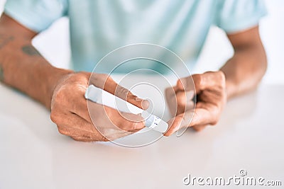 Young hispanic diabetic man measuring glucose level at home Stock Photo