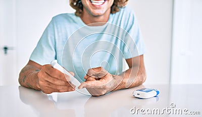 Young hispanic diabetic man smiling happy measuring glucose level at home Stock Photo