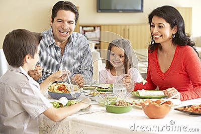 Young Hispanic Family Enjoying Meal At Home Stock Photo