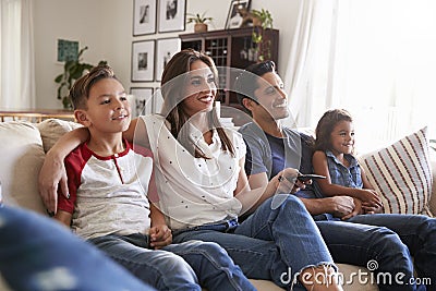 Young Hispanic family sitting on the sofa at home watching TV togther, close up Stock Photo