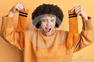 Young hispanic girl holding pair of socks celebrating crazy and amazed for success with open eyes screaming excited Stock Photo