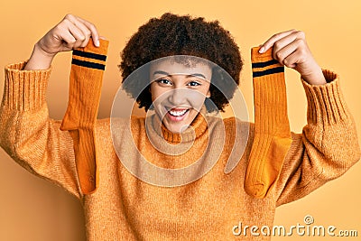 Young hispanic girl holding pair of socks smiling and laughing hard out loud because funny crazy joke Stock Photo