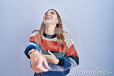 Young hispanic girl standing over blue background laughing at you, pointing finger to the camera with hand over body, shame Stock Photo