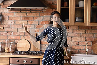 Young hispanic lady singing song aloud by music at kitchen Stock Photo