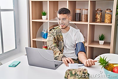 Young hispanic man army soldier using tensiometer at home Stock Photo