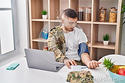 Young hispanic man army soldier using tensiometer at home Stock Photo