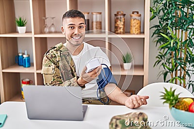 Young hispanic man army soldier using tensiometer at home Stock Photo