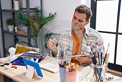 Young hispanic man artist having video call drawing at art studio Stock Photo