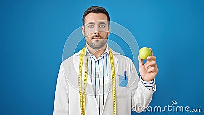 Young hispanic man dietician holding apple over isolated blue background Stock Photo