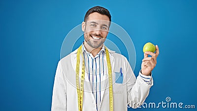 Young hispanic man dietician smiling confident holding apple over isolated blue background Stock Photo