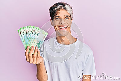 Young hispanic man holding russian 200 ruble banknotes looking positive and happy standing and smiling with a confident smile Stock Photo