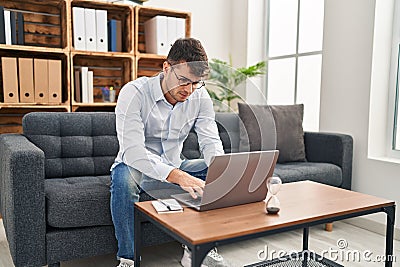 Young hispanic man psychologist using laptop at psychology clinic Stock Photo