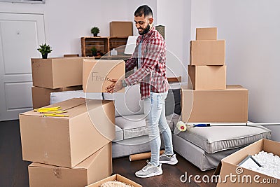 Young hispanic man smiling confident holding fragile package at new home Stock Photo