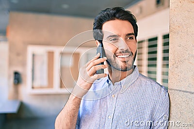 Young hispanic man smiling happy talking on the smartphone leaning on the wall Stock Photo