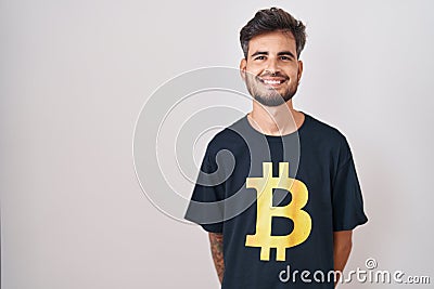 Young hispanic man with tattoos wearing bitcoin t shirt with a happy and cool smile on face Stock Photo
